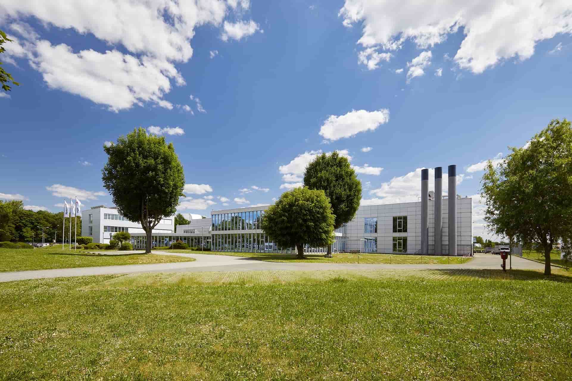 Verwaltungsgebäude der Herbert Gruppe in Bensheim, moderne Glas- und Metallfassade mit Grünfläche und Bäumen im Vordergrund