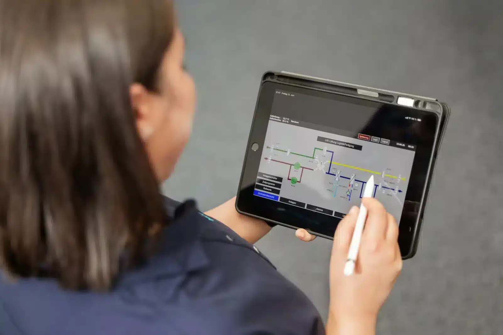 Mitarbeiterin bedient eine Gebäudeautomation-Visualisierung auf einem Tablet